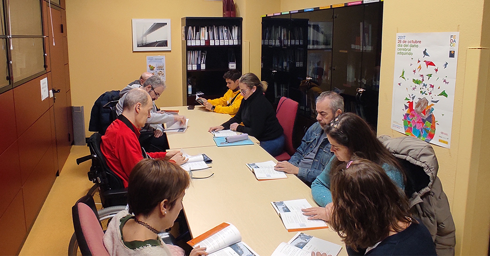 Personas usuarias del Ceadac en la biblioteca del centro durante el taller Club de Lectura Fácil. Con ellas está Silvia Martínez, TCAE del Ceadac.